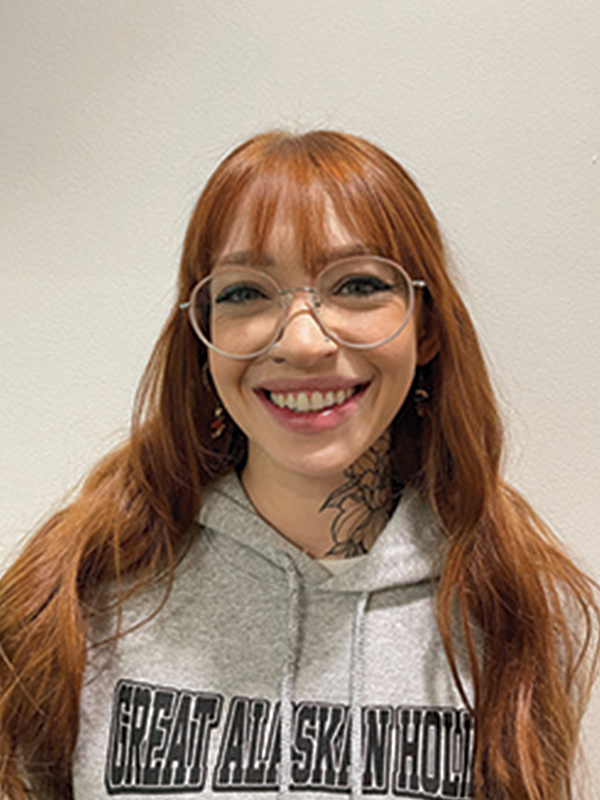 Headshot of a woman with long red hair wearing glasses and a light gray sweatshirt