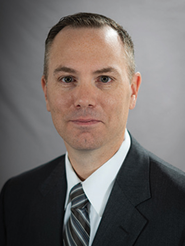 Headshot of a man wearing a suit and tie