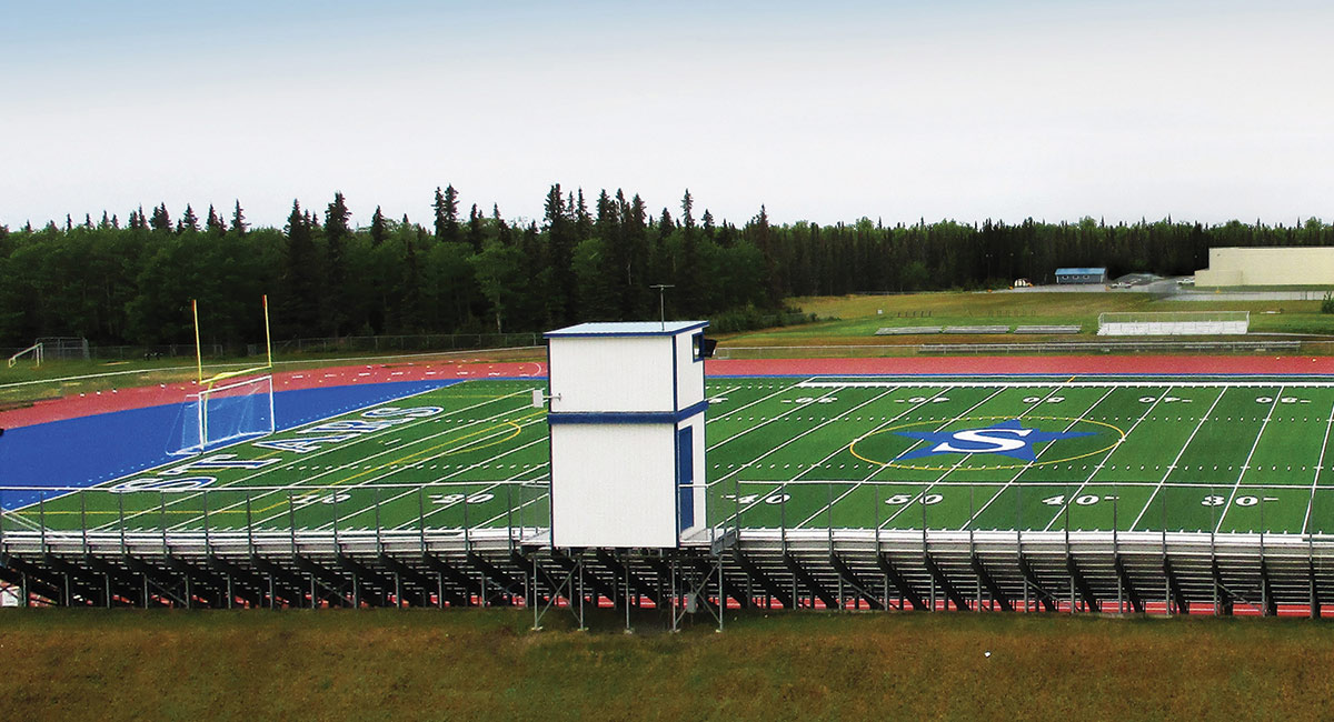 Landscape photograph of the Seward High School football field, bleachers, and circular track around the field on a overcast day