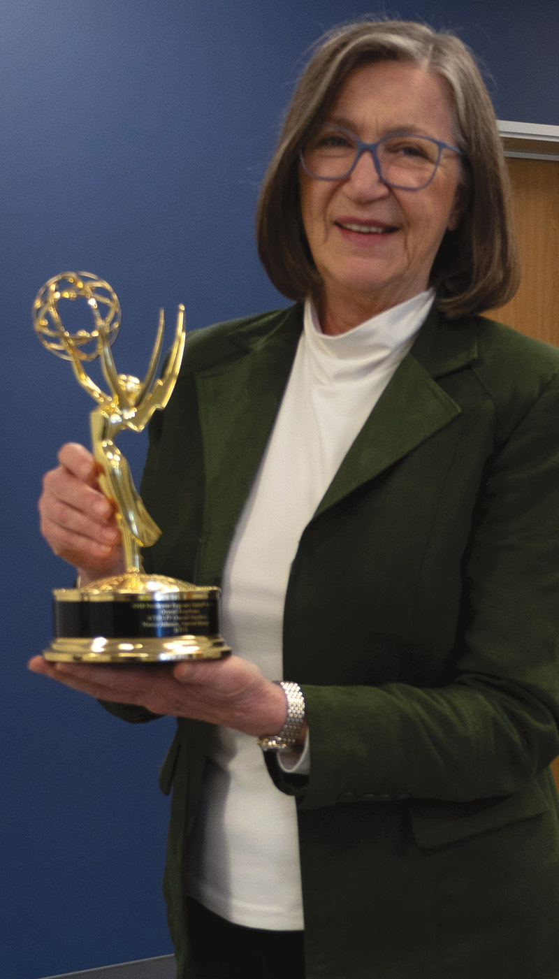 Nancy Johnson holding an award and smiling