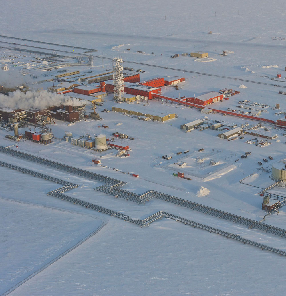 An aerial view of a snow-covered factory, surrounded by a white landscape, showcasing its industrial presence in a wintry setting.