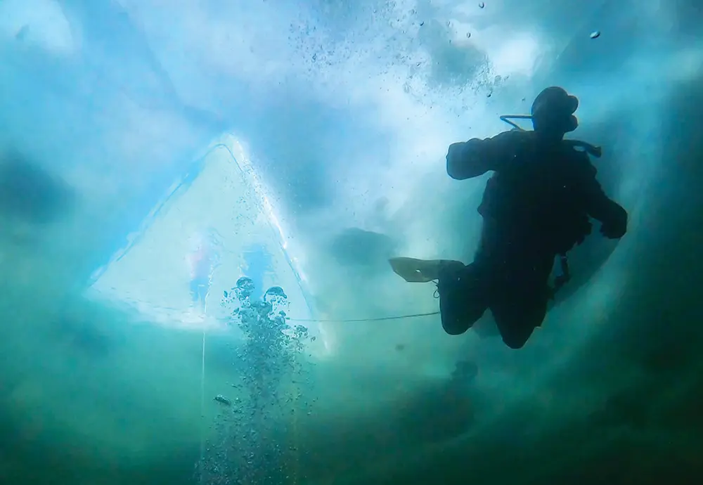 dark underside view of a scuba diver in winter Alaskan waters
