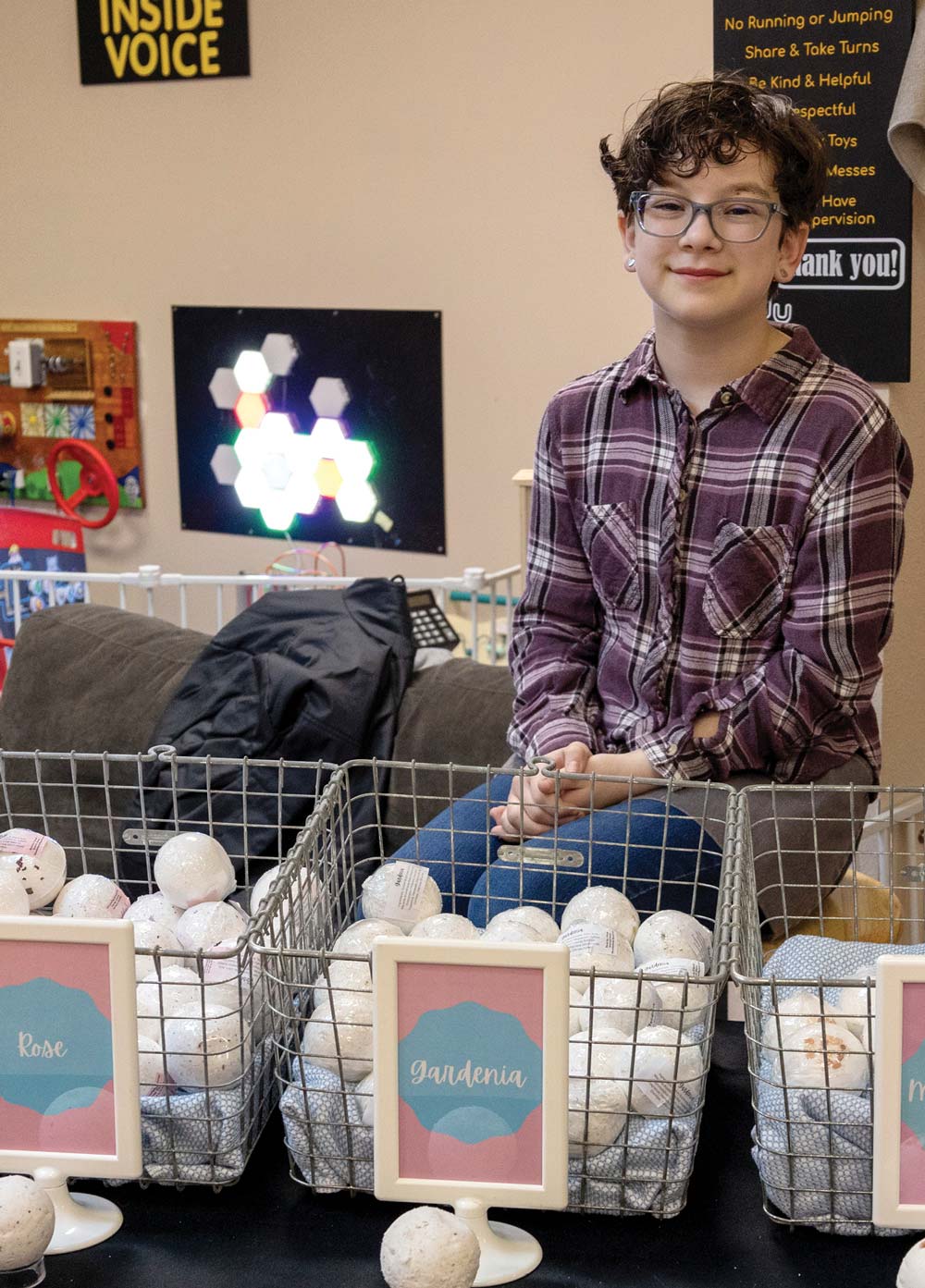 young boy sitting at a booth where homemade bath bombs are being sold