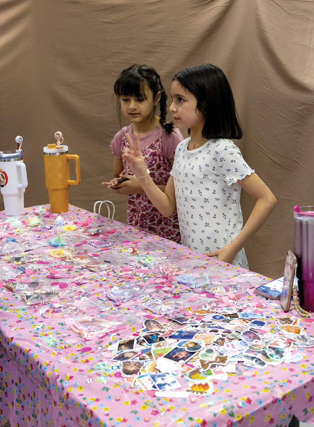 two young girls selling homemade bracelets and stickers at a booth