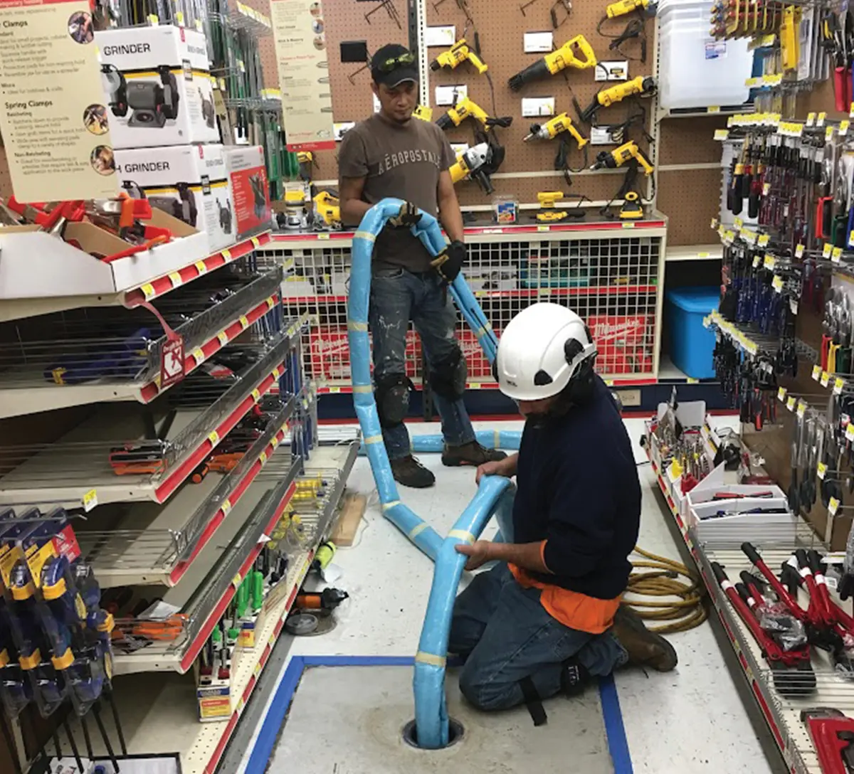 workers running a pipe through the floor