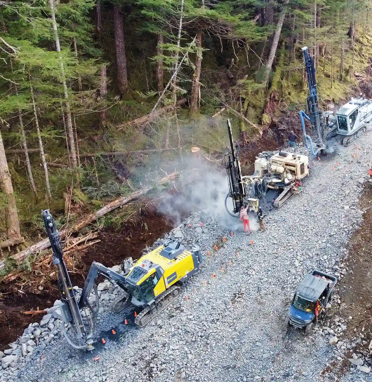 crew using construction vehicles to create a path through the wilderness