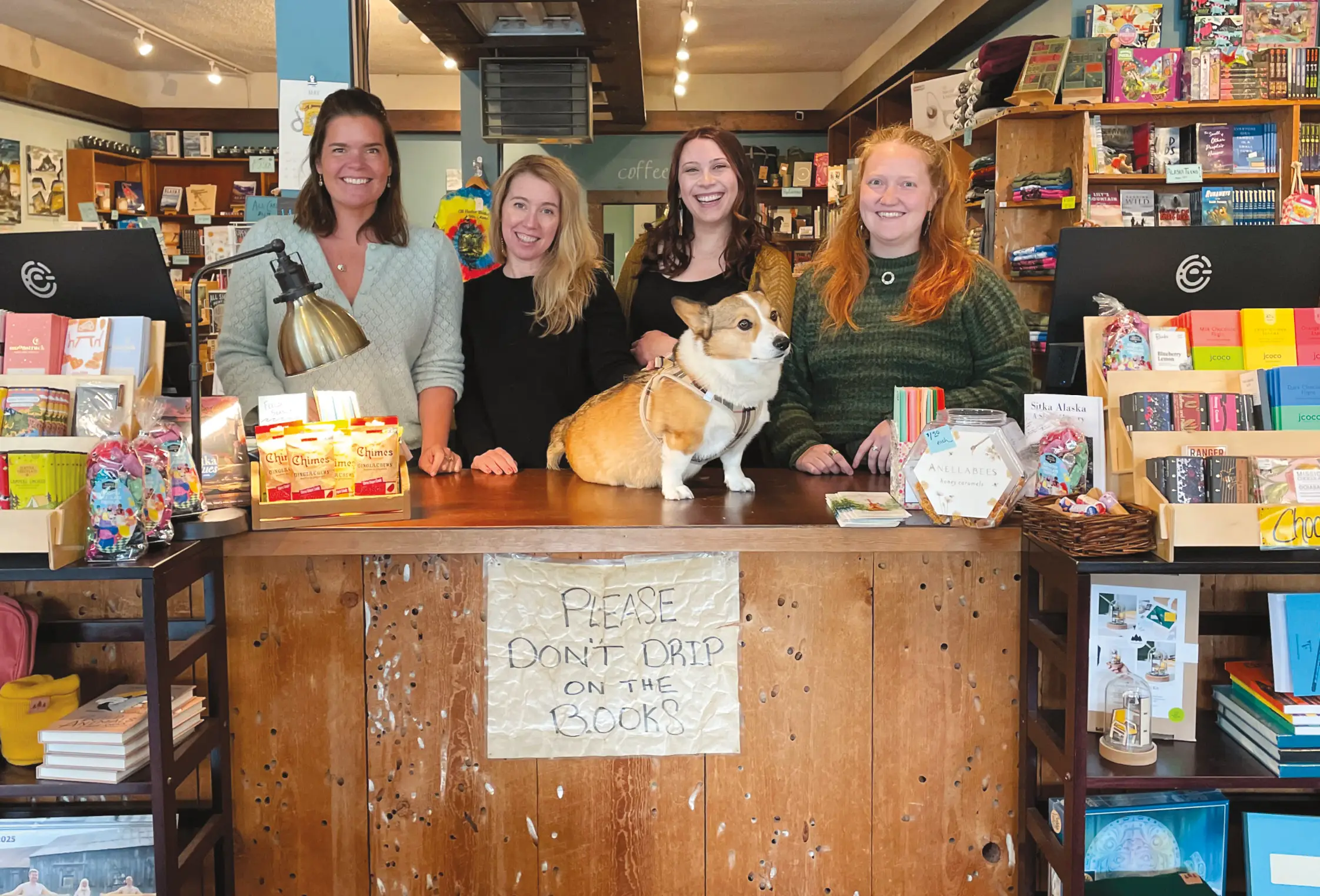 group photo of workers in a bookstore with dog on desk