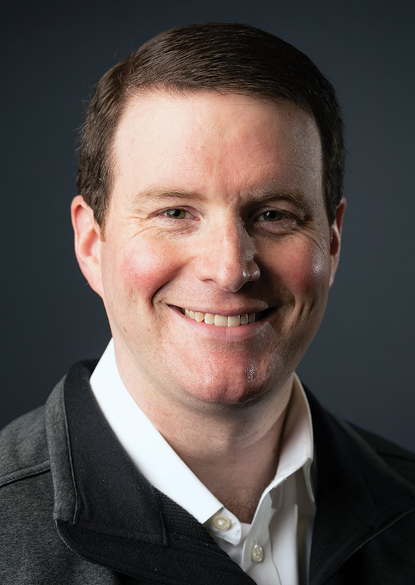 Portrait headshot photo of Greg Gallagher smiling