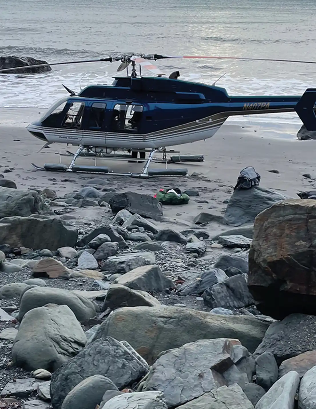 a helicopter rests on a beach during GeoAlaska's geophysical surveys on the south side of Augustine Island in 2023