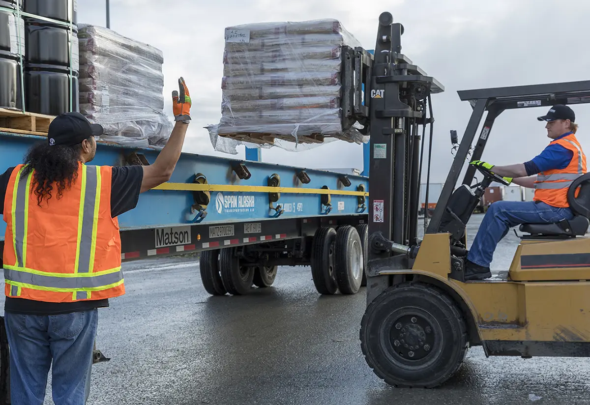 Span Alaska workers loading bricks onto a flatbed using a forklift