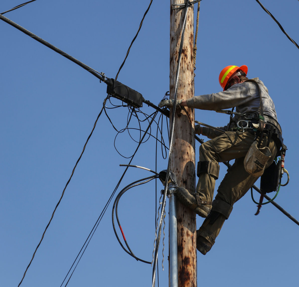 lineman working with wires on top of a pole
