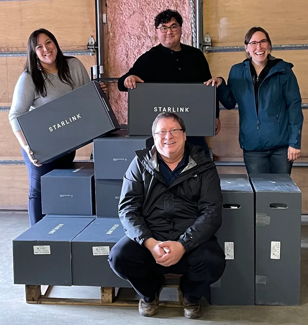 four people posing with Starlink satellite internet boxes