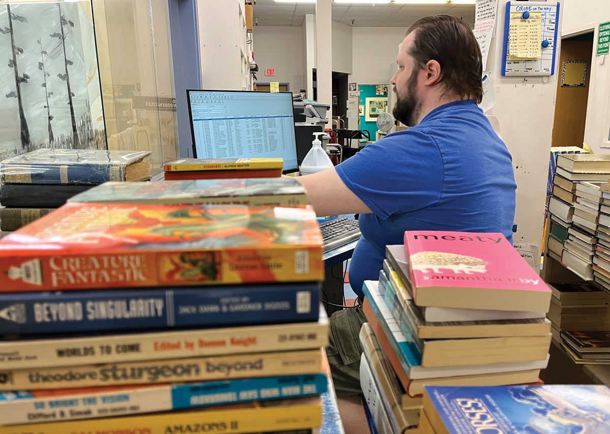 A man engaged in computer work while seated at a desk amidst rows of books and study areas