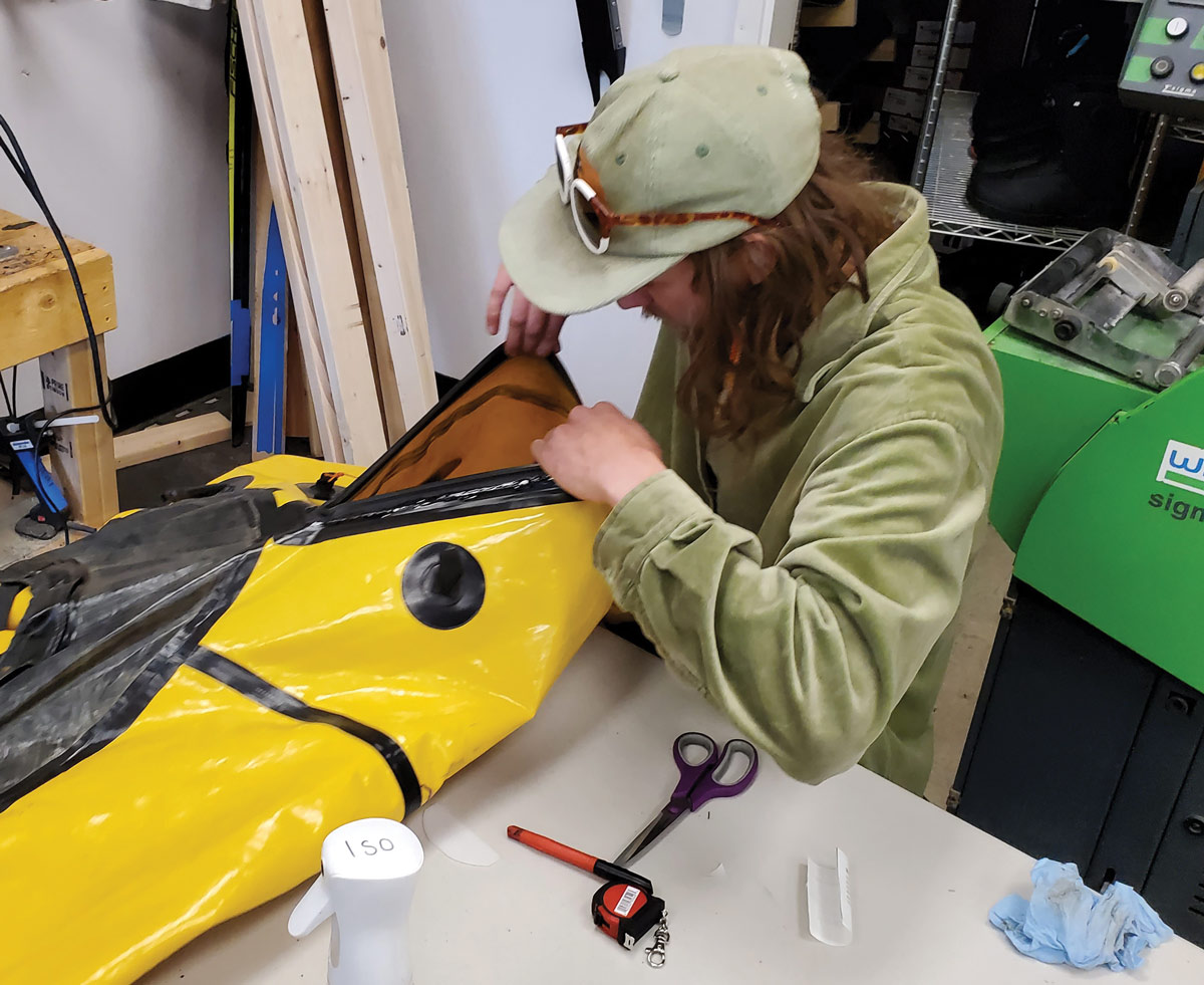 man in a green jacket inspecting a piece of merchandise for repair