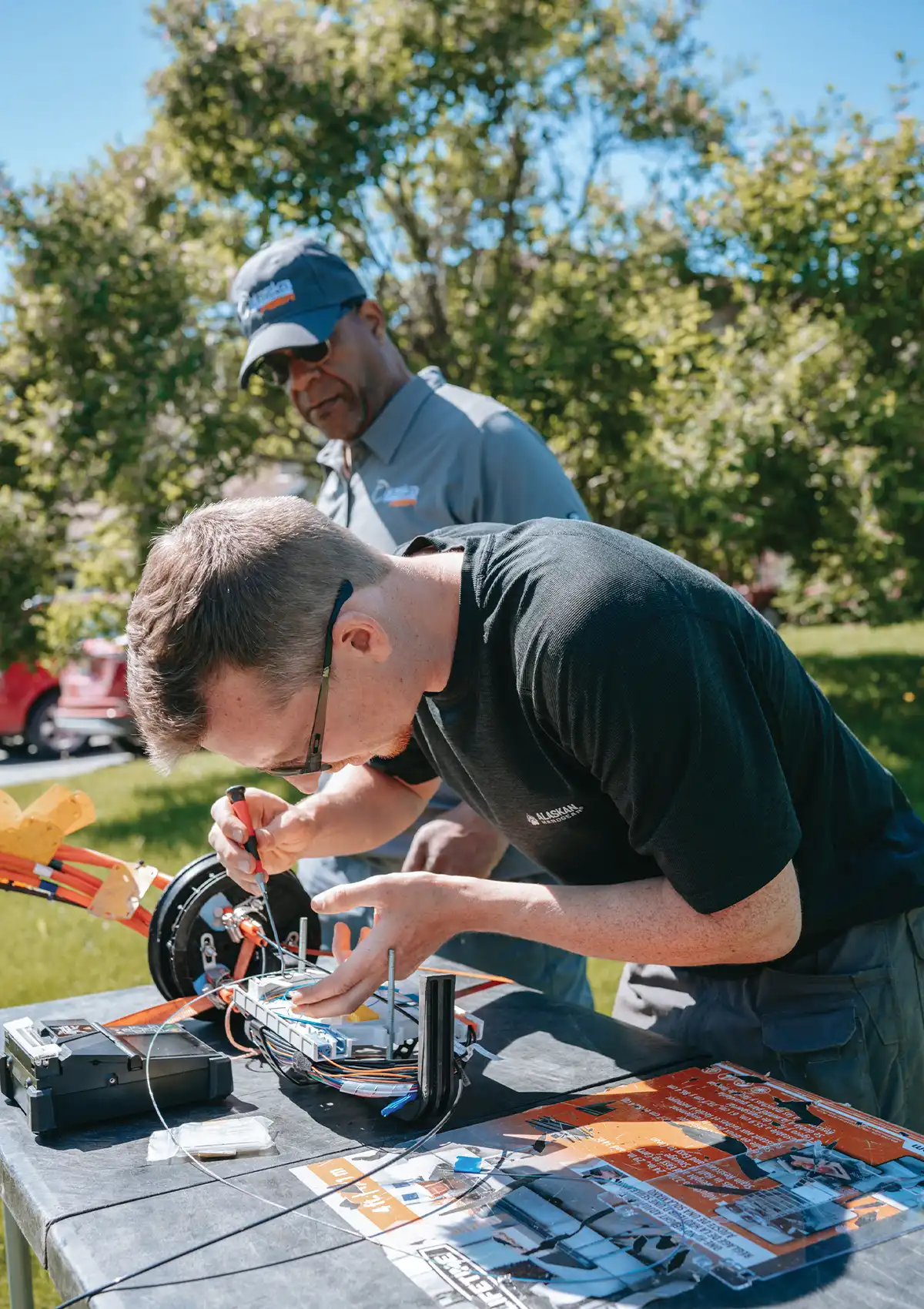 Alaska Communications apprentice Korey Pugh works on a device as journeyman Richard Burton watches on the side