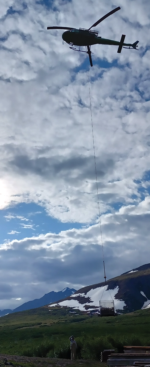 upward view at a helicopter carrying Graphite Creek mine core samples from the 2023 drilling season