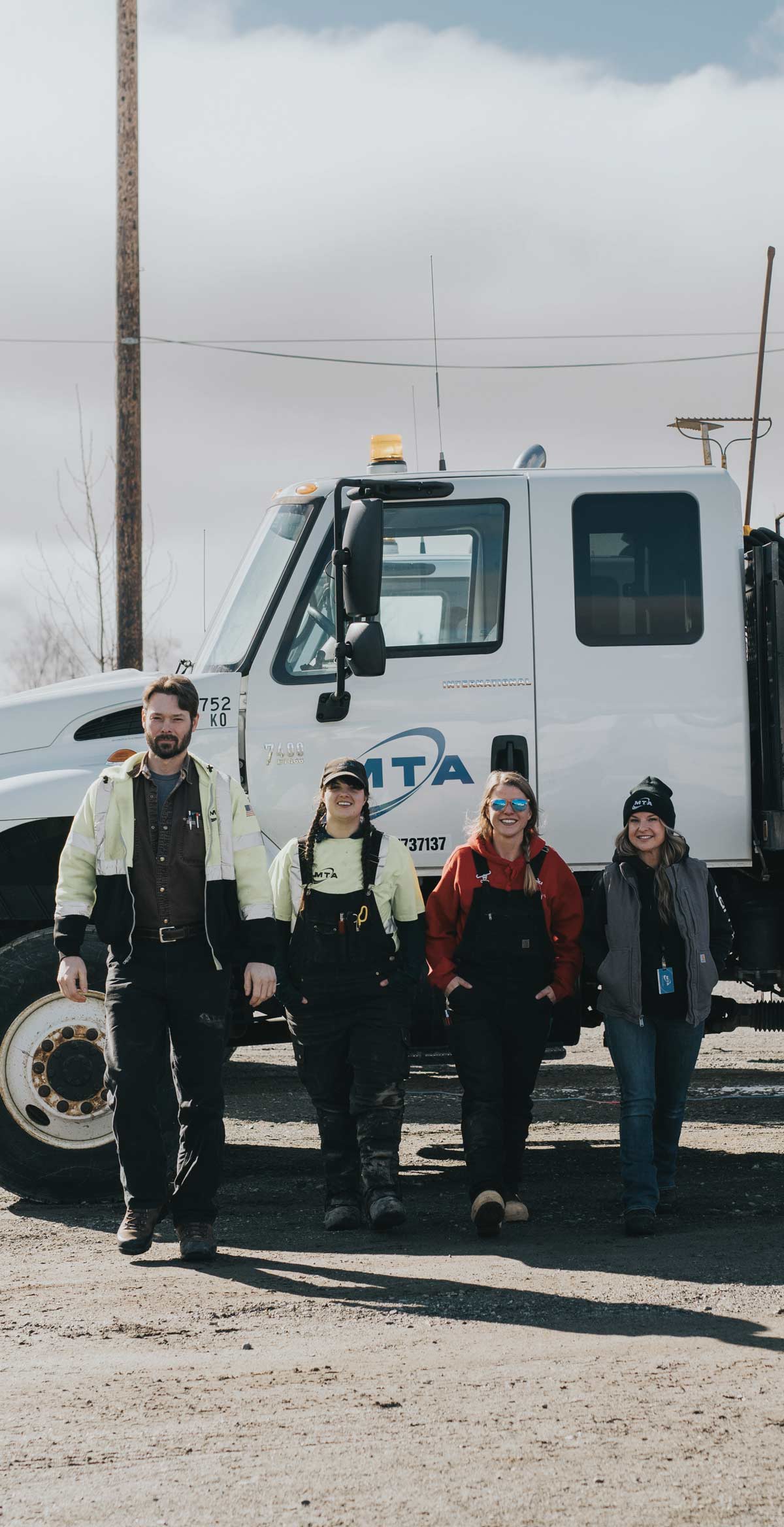 four people smiling while walking away from a truck 