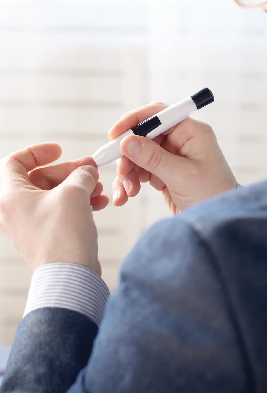 close cropped view of a persons hands conducting a blood glucose test