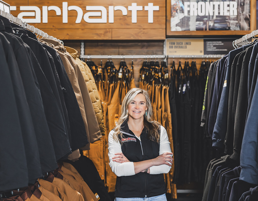 Jessica Rostad smiling with arms crossed in front of aisles of merchandise