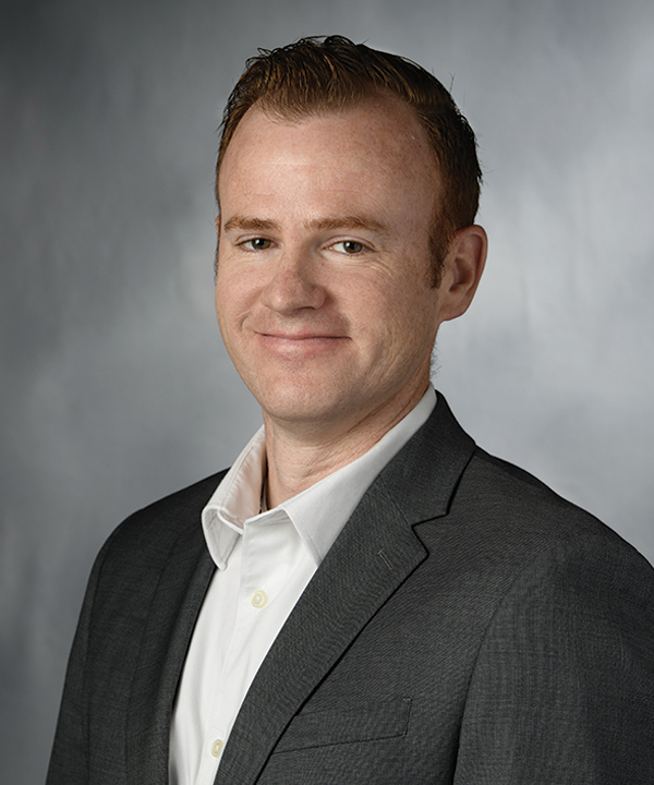 Portrait headshot photograph of Aaron Smith grinning