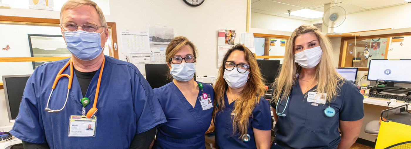 Four people all wearing face masks and scrubs posing for a group photo