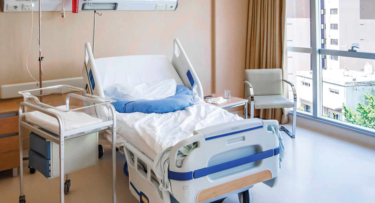 empty hospital newborn bed with bassinet next to it
