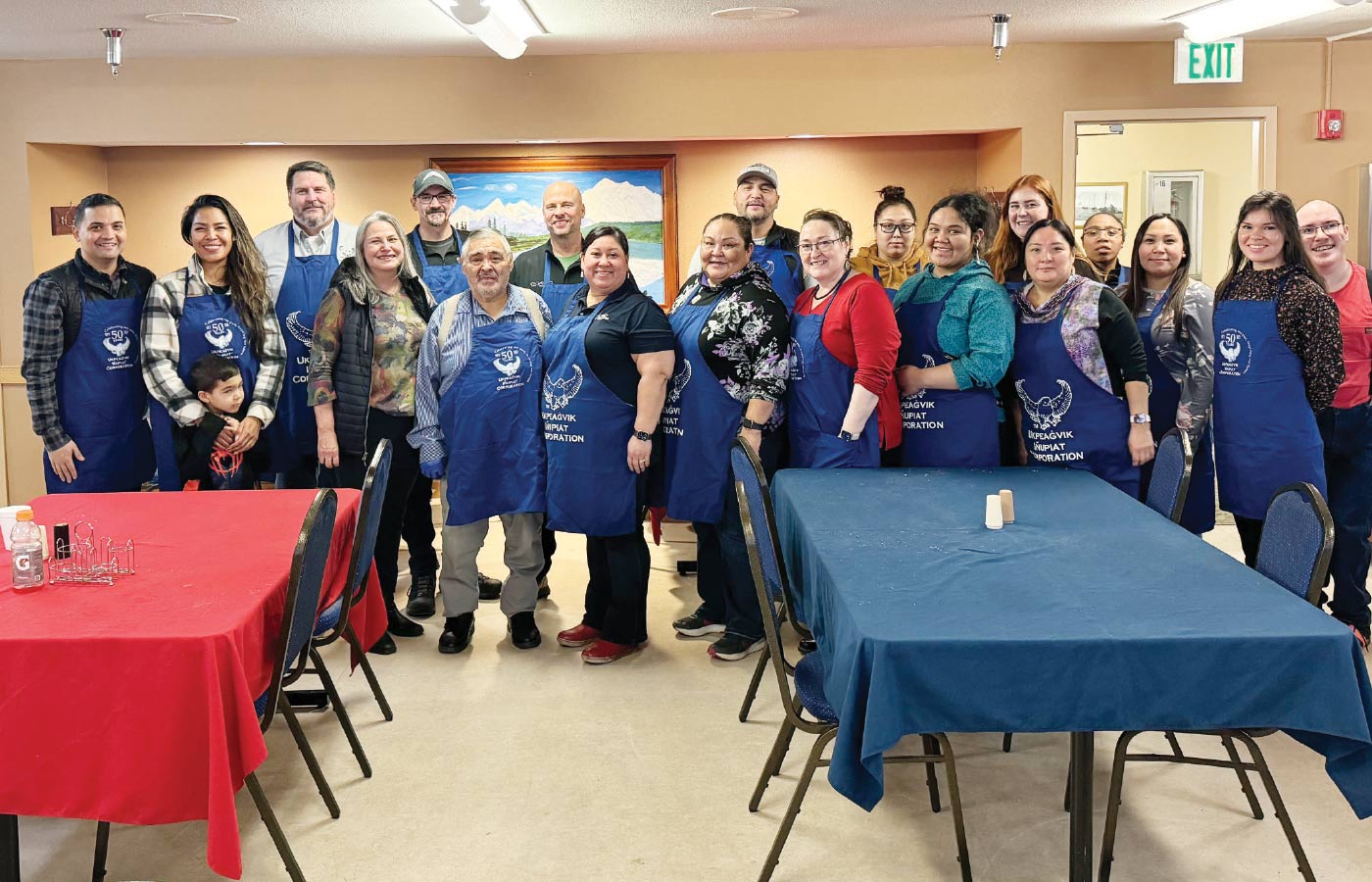 Ukpeaġvik Iñupiat Corporation board and staff wearing blue aprons to serve at the 2024 Elders Thanksgiving Luncheon in Utqiaġvik
