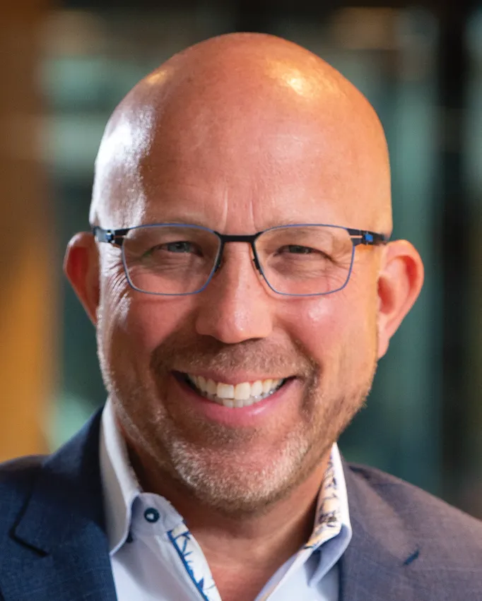 Portrait orientation close-up headshot photograph of Allen Debes smiling