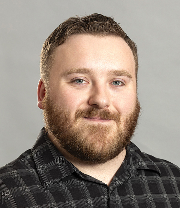 Portrait orientation close-up headshot photograph of Owen Rohler grinning