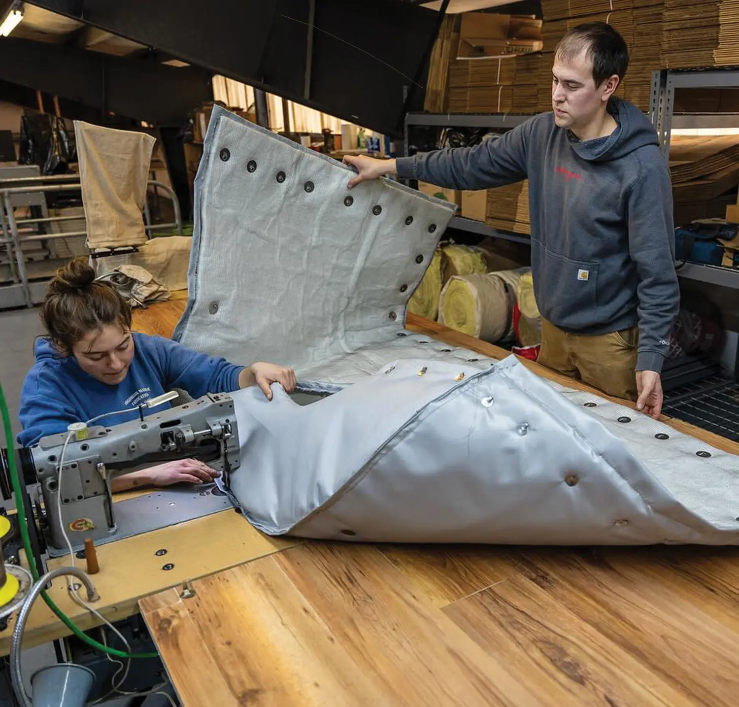 a man and a woman from the Salamander crew work together fabricating an exhaust insulation wrap