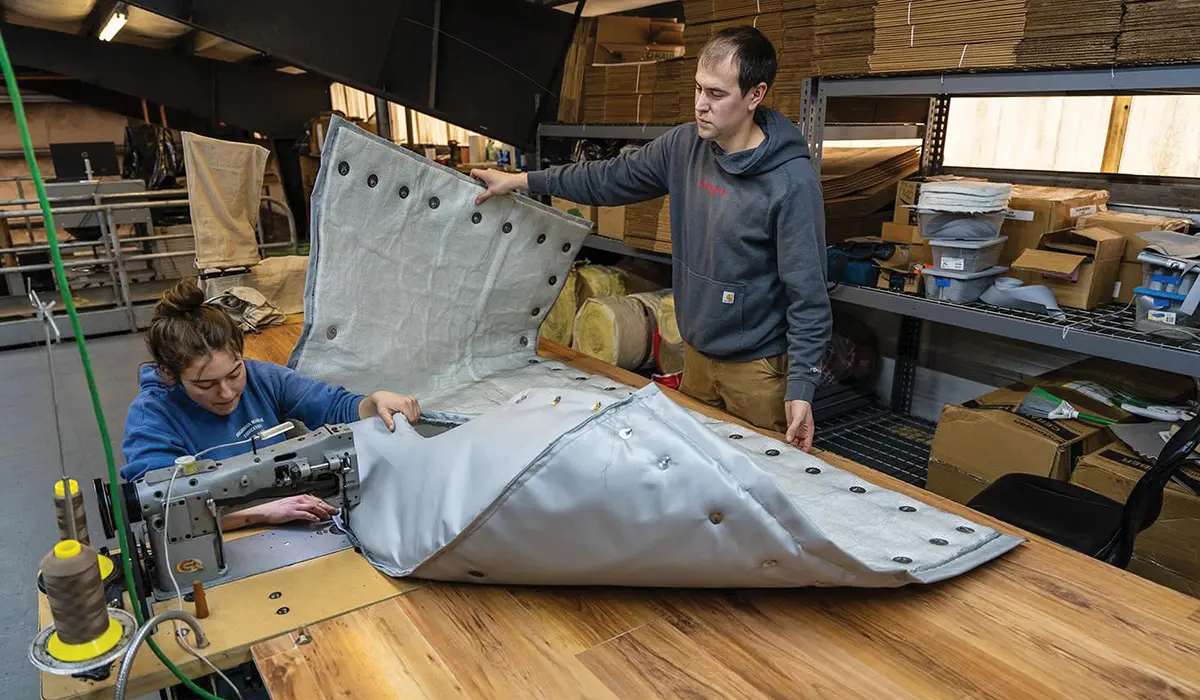 a man and a woman from the Salamander crew work together fabricating an exhaust insulation wrap