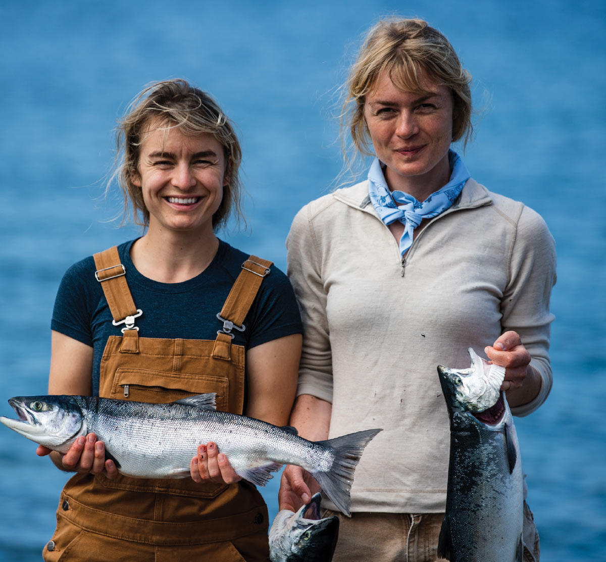 two women holding fish and smiling 