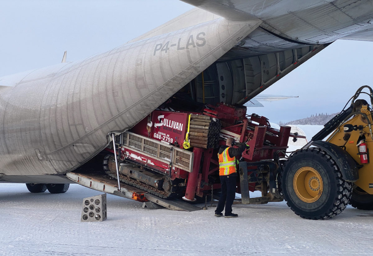 Sullivan Water Wells crew unloading a Nordic Drill from the belly of a C-130 Hercules