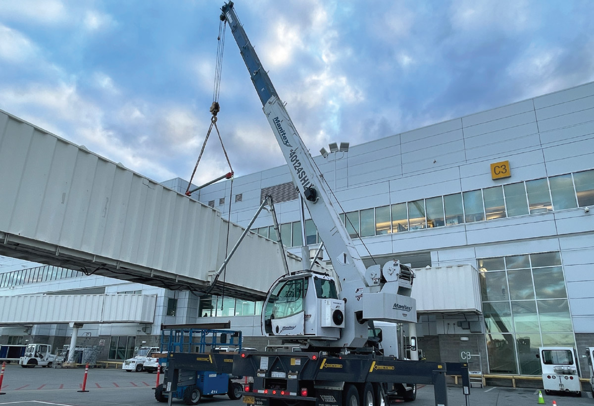 Crews using a 40-ton crane to assist in repairing a jet bridge