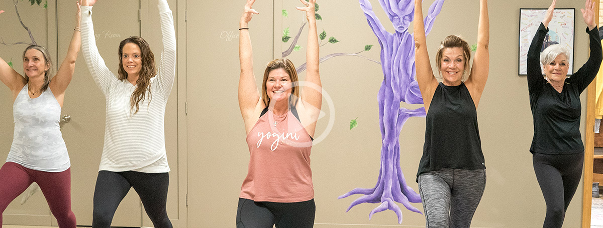 screen capture from a video of a five of woman performing a standing pose during a yoga session