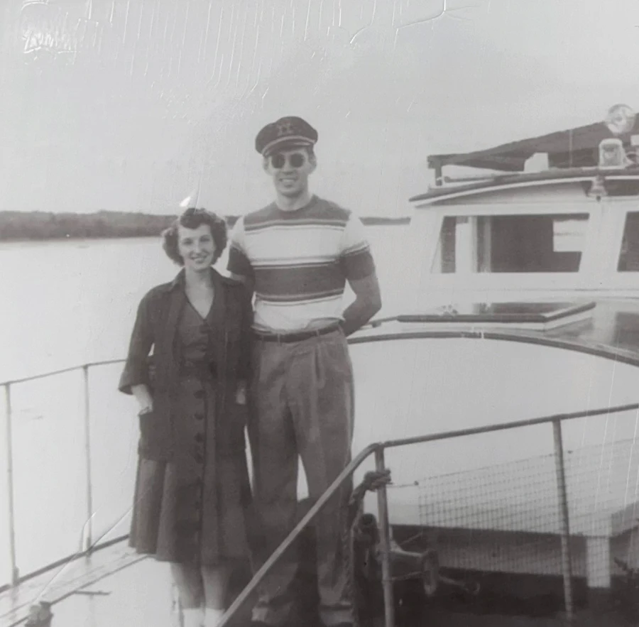 black and white photo of a man and a woman posing in front of a steamship