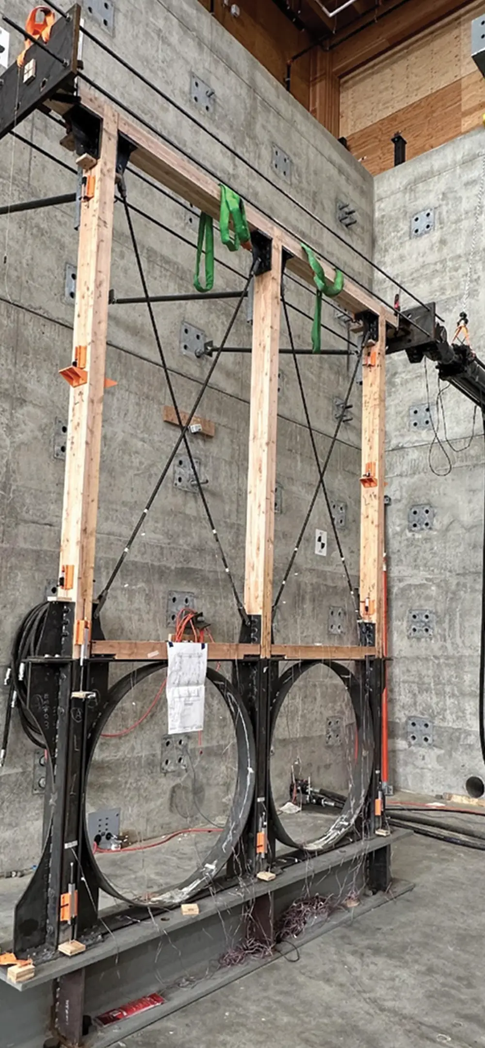 A large, wooden and steel frame structure with circular bases being tested against a concrete wall.