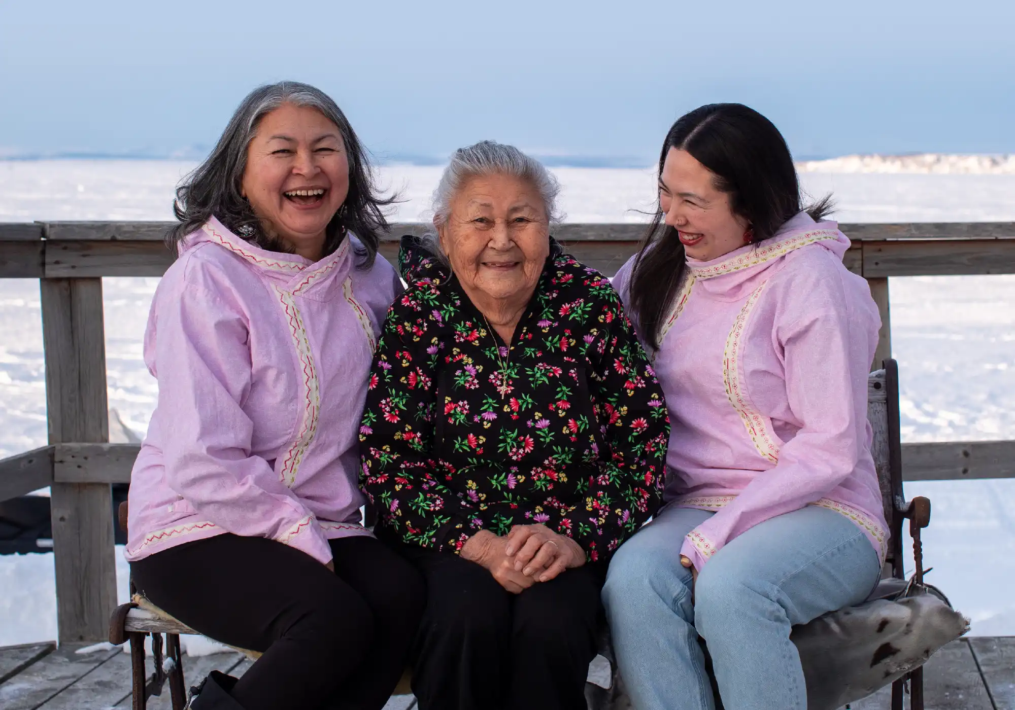 three women of different generations laughing together with a snowy landscape in the background