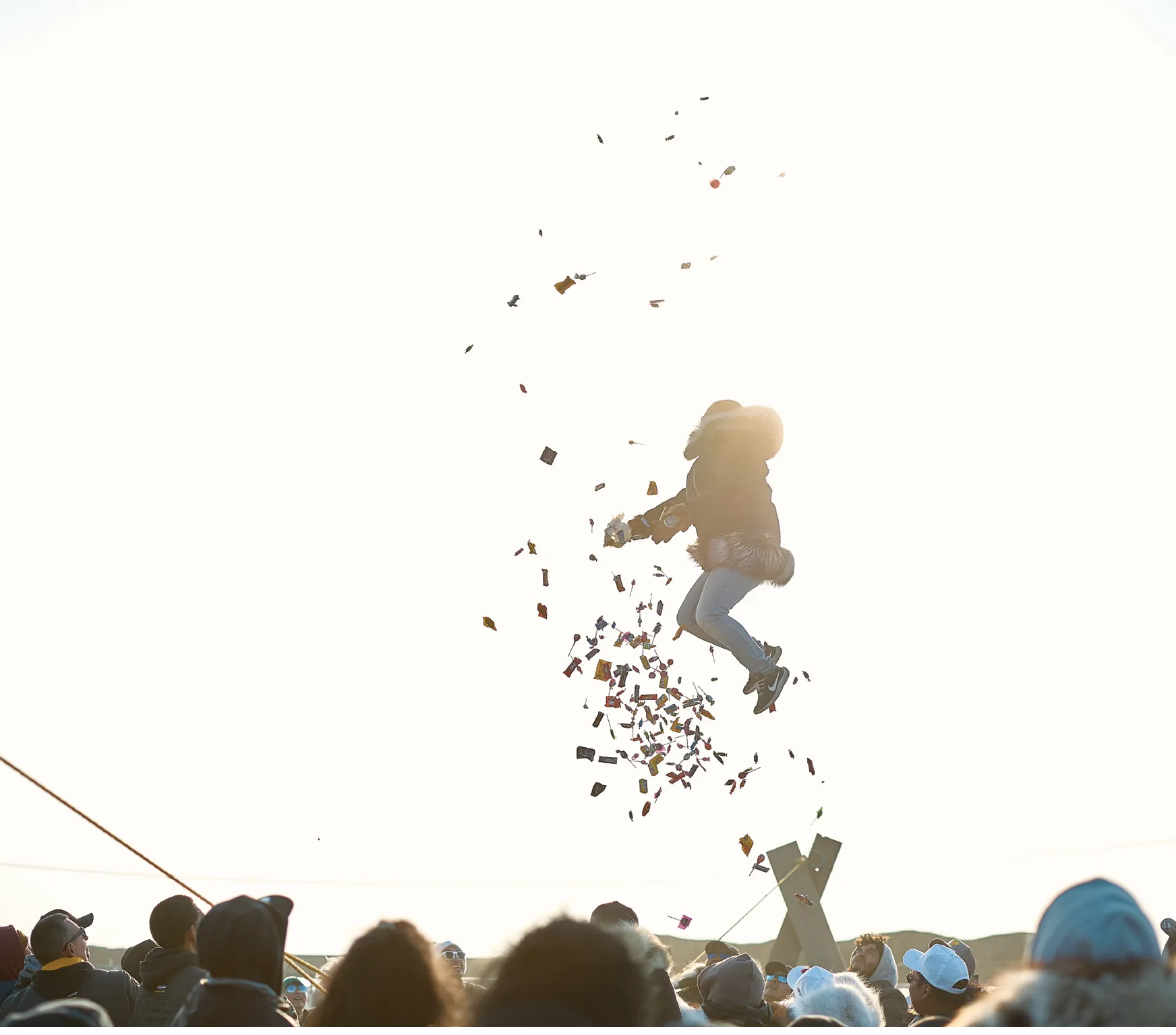 Person jumping in the air with colorful confetti falling around them, surrounded by a crowd.