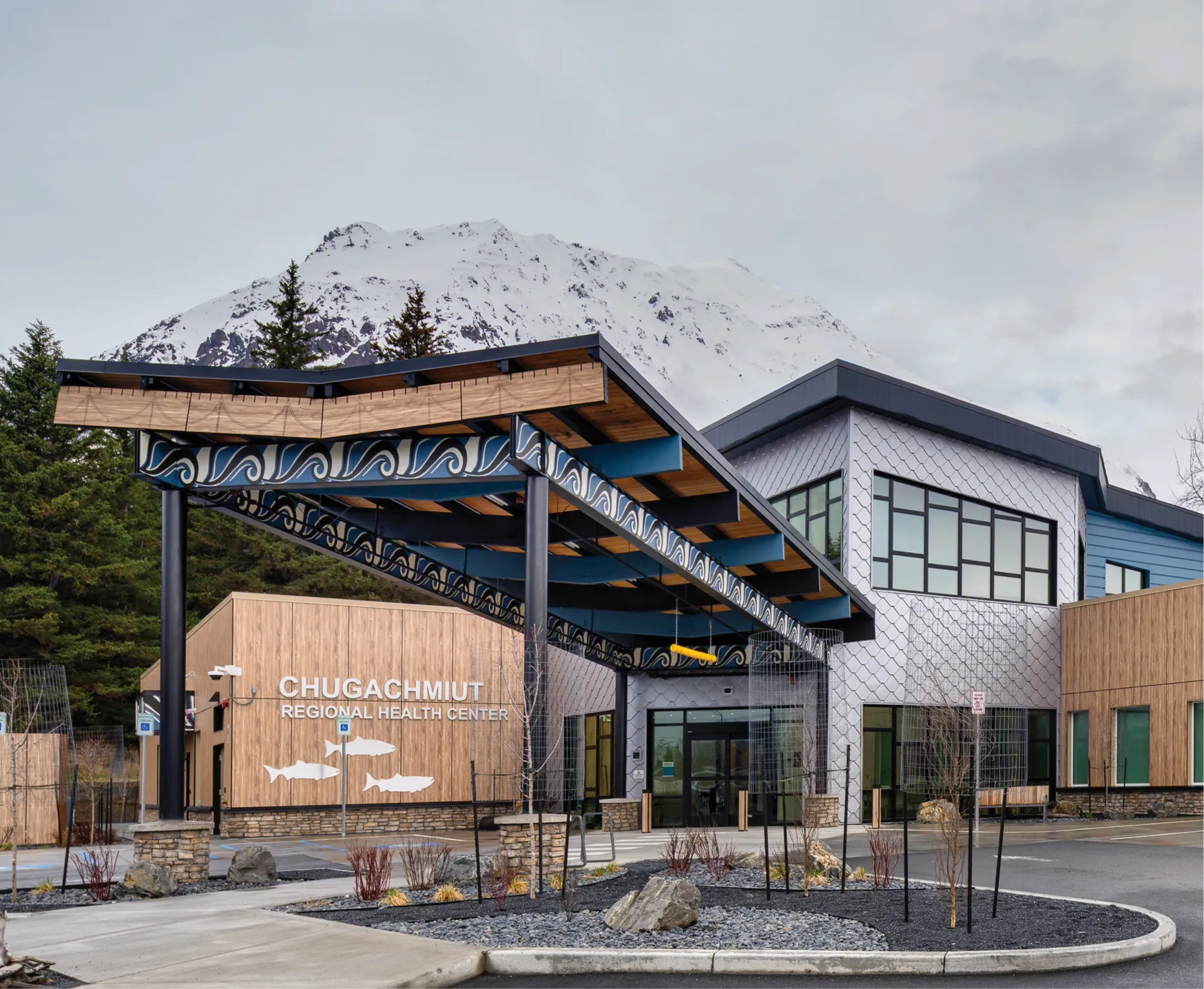 Chugachmiut Regional Health Center building with mountain backdrop and decorative roof design.