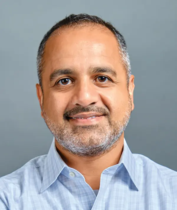Portrait orientation photograph close-up headshot view of Yasir Alvi smiling