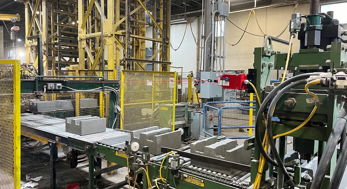 Industrial equipment and concrete blocks on a conveyor belt at Anchorage Sand & Gravel’s block plant, where aggregate, cement, and water are mixed to produce various concrete products.