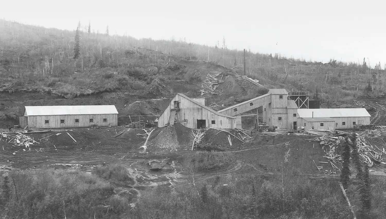 Historic black and white photograph of the Red Devil Mine processing plant and buildings built into the rugged Alaskan hillside