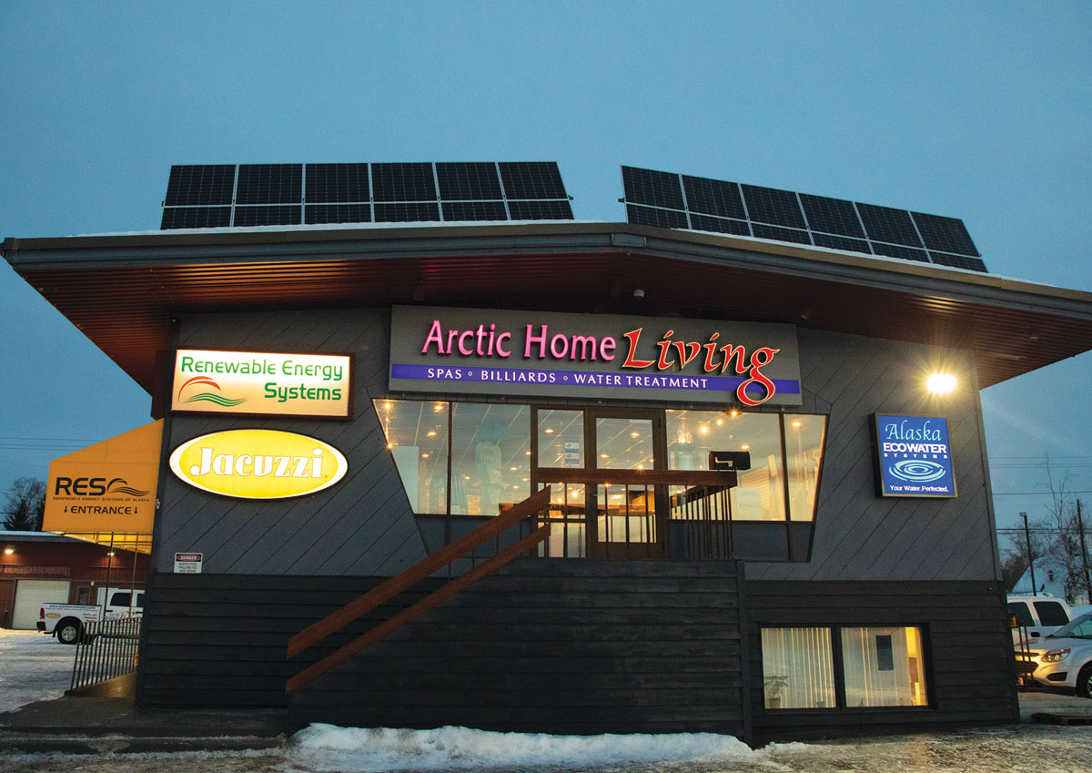 Commercial building, "Arctic Home Living," with solar panels on the roof and signs for Renewable Energy Systems and Jacuzzi.