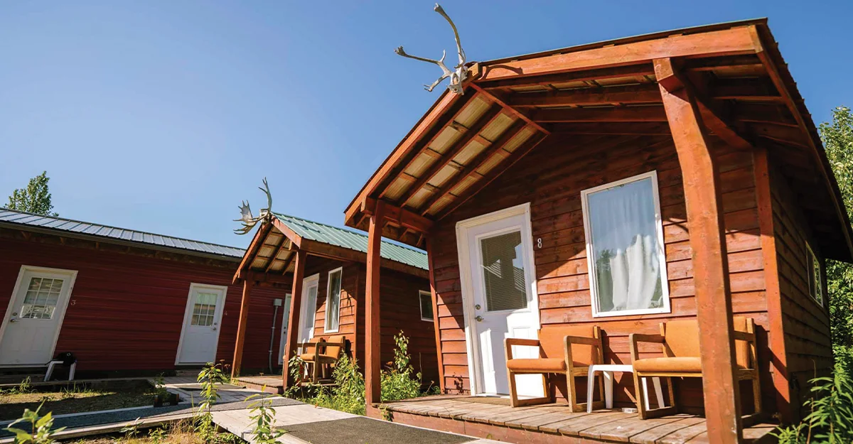 Small wooden cabins at an Alaska remote workforce housing site, featuring rustic timber siding and decorative moose antlers on the roof peaks.