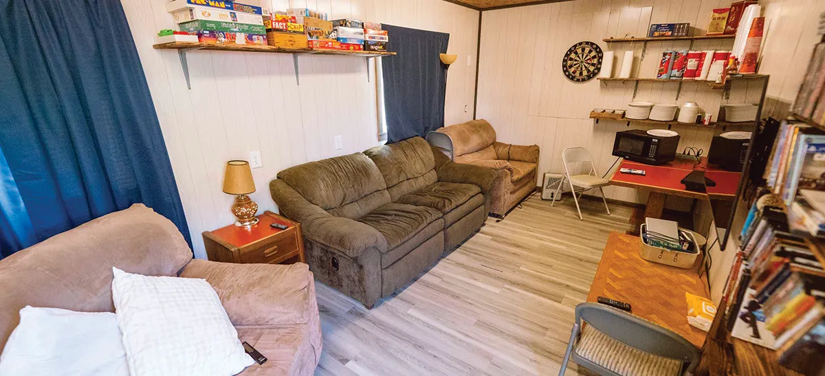 Common room in a remote workforce housing facility featuring comfortable sofas, a collection of board games, and a dartboard.