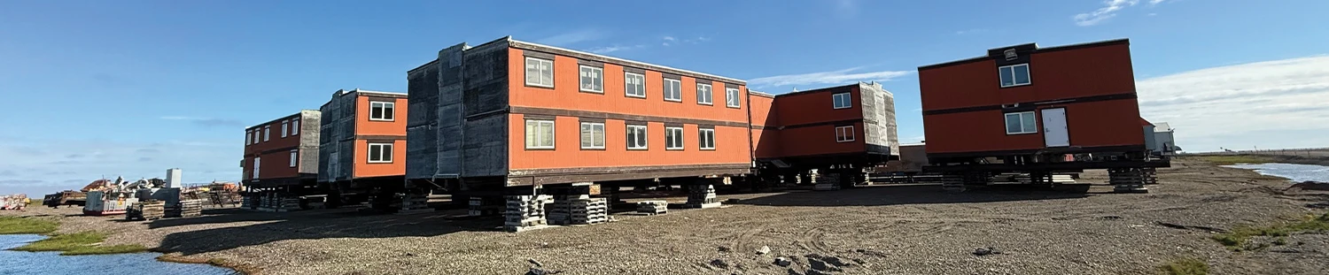 Row of prefabricated orange shipping container-style worker accommodations at a rural job site camp.