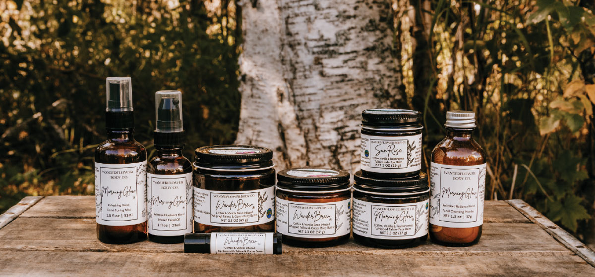 A set of Wanderflower Body Co. "WanderWild" products, featuring an exfoliating powder cleanser, facial mist, and face balm.