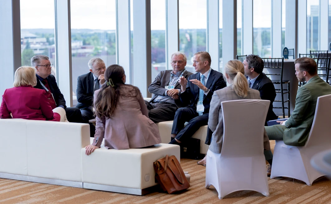 Conference participants sit in a small circle during a facilitated discussion session at the Arctic Encounter Summit, with attendees actively listening and speaking in a bright meeting space.