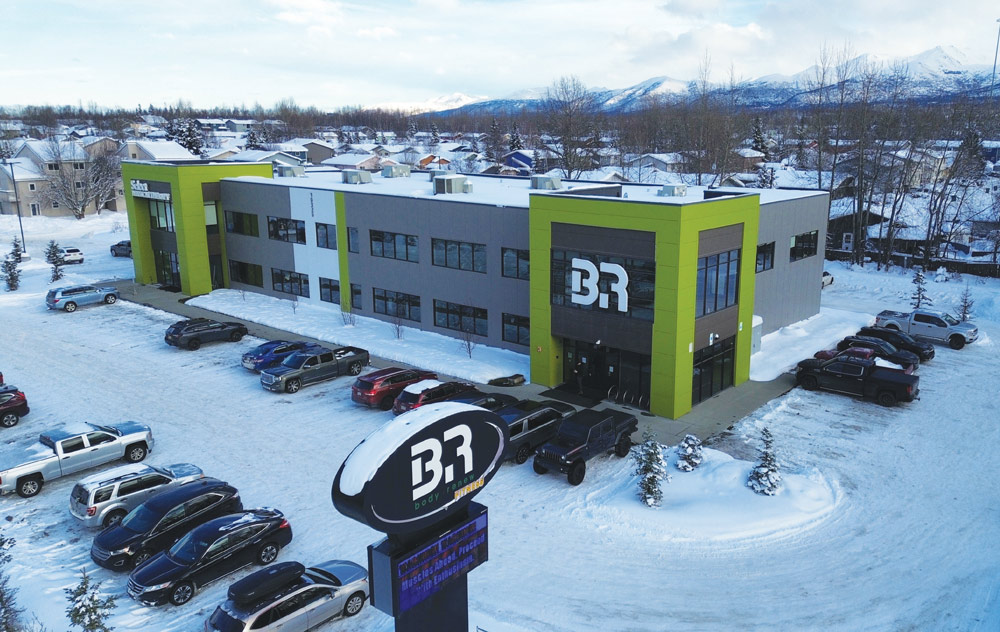 Aerial view of Body Renew Fitness, a modern grey and lime green building in a snowy Alaskan landscape.